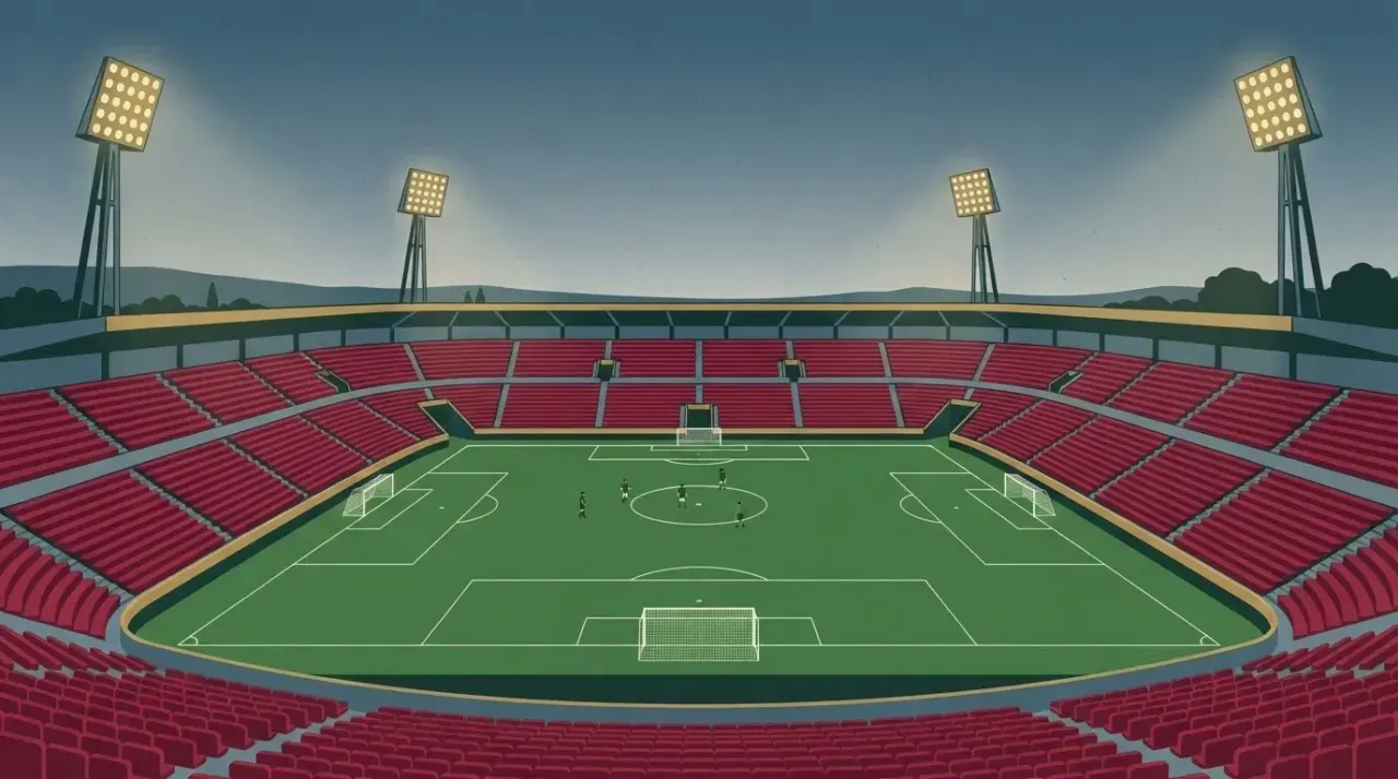 Stadion piłkarski z zieloną murawą i bramkami, oświetlony, z pustymi trybunami i kilkoma małymi postaciami graczy w…